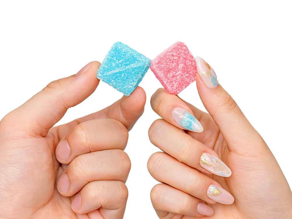 SEXTASY ORIGINAL のソーダ味とピーチ味のグミを一人1粒ずつ持っているところ